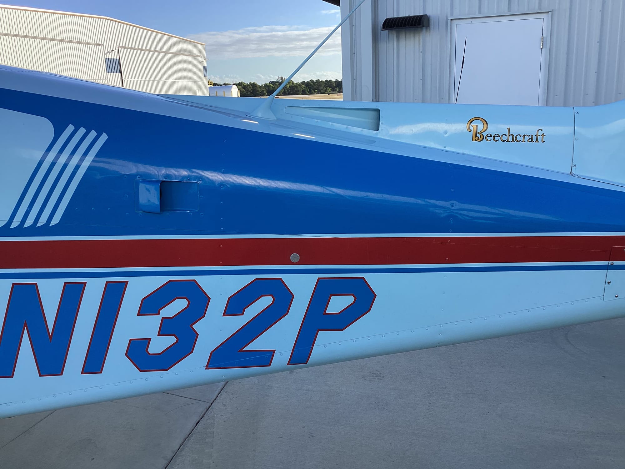 A blue-and-white Beechcraft Sundowner on the ramp at Islander Aviation
